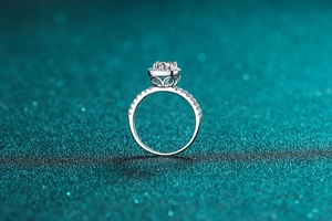 Detail view of moissanite ring showing halo setting and pavé diamonds on a blue background