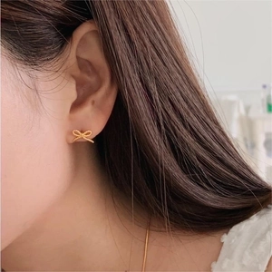 Elegant 925 sterling silver bow earrings with gold finish on female model ear