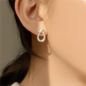 Minimalist 925 sterling silver knot stud earrings worn by a model in a side view