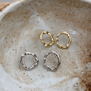 Detailed view of gold and silver irregular textured earrings in a ceramic bowl