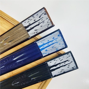 Detailed side view of three folded Japanese bamboo fans on a light wooden tray