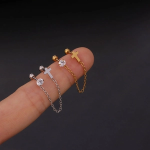 Detail of silver and gold chain earrings with zircon studs and hanging cross charms
