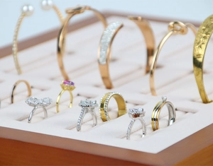 Detail view of rings and bracelets displayed on beige velvet jewelry storage tray