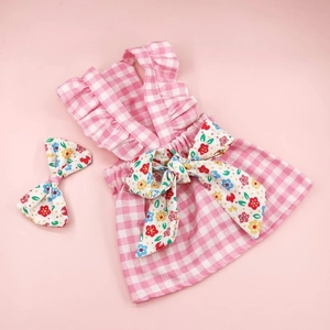Detailed flat lay of pink checkered dog dress with a matching floral bow accessory