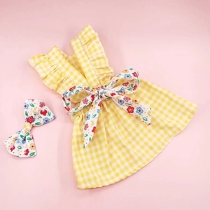 Detail of yellow plaid dog dress with floral bow and matching pet hair accessory