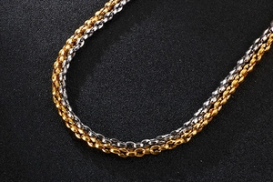 Makroaufnahme von gold- und silbernen Edelstahl-Kettengliedern auf schwarzem Hintergrund