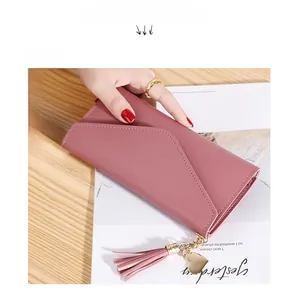 Detailed view of pink long wallet with heart pendant and tassel on wooden surface