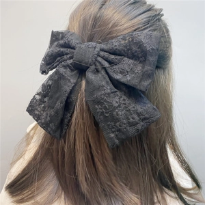 Detailed view of large black lace bow hair clip worn on long hair for back-style look