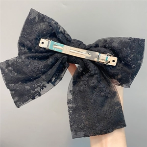 Close-up of black double-layered lace bow hair clip with silver metal spring fastener