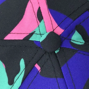 Macro detail of camouflage baseball cap top button showing vibrant twill fabric and stitching
