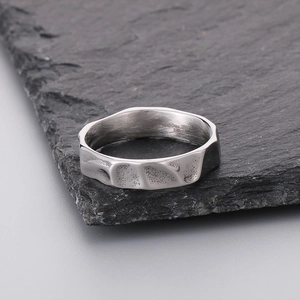 Macro shot of 316L stainless steel ring with irregular texture on a dark stone surface