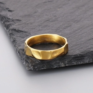 Detailed close-up of golden textured stainless steel ring on a black stone base
