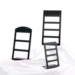 Set of three black acrylic earring display stands in various sizes on white fabric