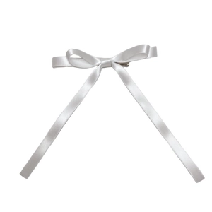 Detailed close-up of a white satin double bow hair clip with a metal alligator base