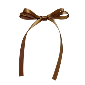 Detail of elegant double-layered brown satin bow hair clip with long flowing ribbons