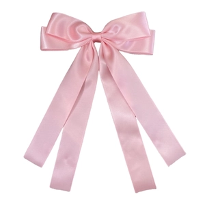 Detailed close-up of pink silk satin double bow hair clip with elegant long ribbon streamers