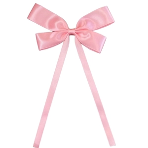 Detail view of a soft pink satin ribbon hair bow with long flowing streamers