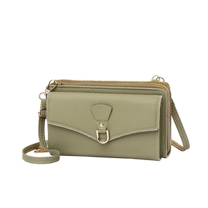 Detail view of the green lychee pattern leather texture and dual zipper compartments