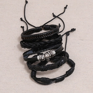 Detail of vintage braided black leather bracelet set with a silver skull charm focal point