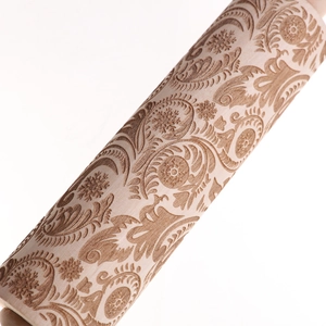 Close-up of intricate paisley and floral wood carvings on a wooden rolling pin