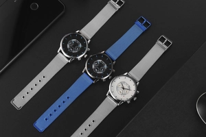 Three men's quartz watches with mesh metal straps and calendar dials on black texture