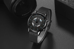 Detail of black mesh band watch with minimalist three-eye dial and calendar window