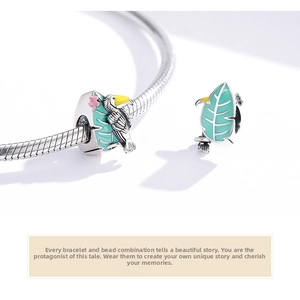 Macro detail of S925 sterling silver toucan and leaf charm with colorful enamel