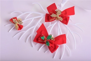 Detailed view of red Christmas bows with gold holly leaves and bells on a white display