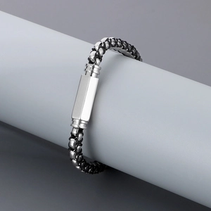 Macro view of woven black leather cord and polished silver metal plate on this hip-hop bracelet
