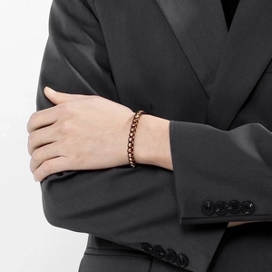 Close-up of a men's brown braided leather bracelet with metal links on a model wrist