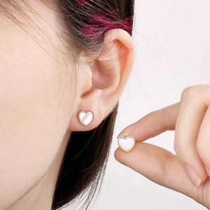 Detail of 18K gold plated heart stud earrings with white mother of pearl inlay on model