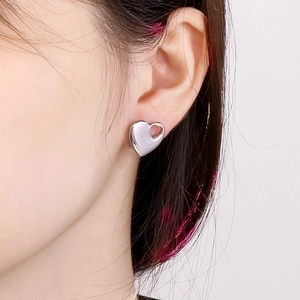 Close-up of silver heart-shaped earrings with solid and hollow nested design for women
