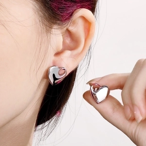Detailed close-up of hollow heart-shaped silver earrings with polished mirror finish