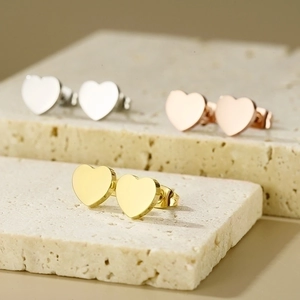 Detailed close-up of heart-shaped earrings in gold and silver on travertine stone
