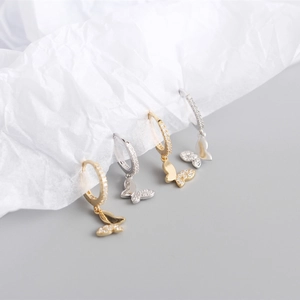 Détail macro de boucles d'oreilles papillon en argent S925 avec cristaux pavés dorés et argentés