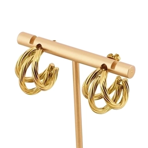 Elegant gold multi-layer twisted C-shape hoop earrings displayed on a minimalist stand