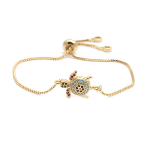 Adjustable gold turtle bracelet with turquoise and zircon stones on a white background