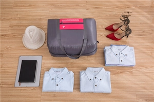 Flat lay of a grey foldable travel bag with pink pockets on a wooden floor