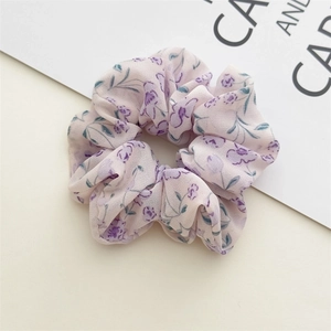 Close-up of light pink chiffon scrunchie featuring a delicate purple floral pattern print