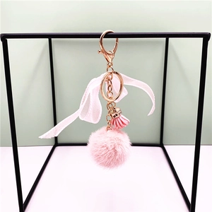 Pink plush ball keychain with a silk bow, leather tassel and rose gold hook detail