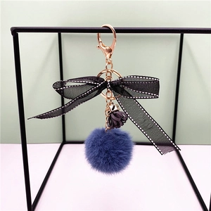 Detail of dark blue plush keychain with black polka dot bow and rose gold clasp