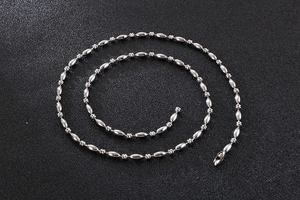 Detailed macro shot of silver stainless steel ball bead chain on black textured surface