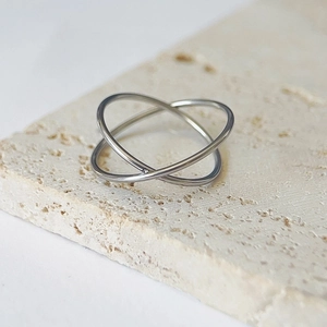 Detail shot of a silver interlaced double ring set on a natural travertine stone surface