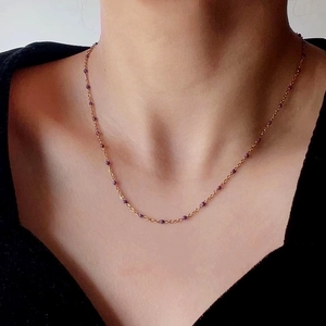 Minimalist 18k gold plated titanium necklace with small purple beads on a woman neck