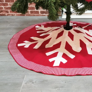 Close-up of a burgundy knit Christmas tree skirt with large white snowflake patterns