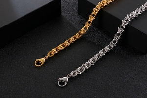 Close-up of gold and silver Byzantine chain bracelets with lobster clasp on black background