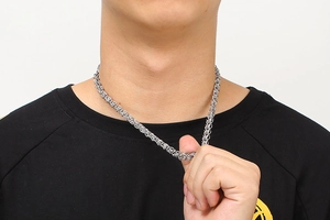 Detail view of a silver stainless steel braided chain necklace worn on a model neck