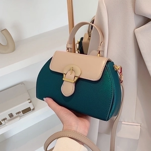 Close-up of contrast color handbag with dark green lychee leather and gold buckle