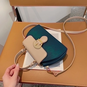 Detail view of emerald green metallic handbag with beige leather top handle and gold clasp