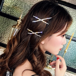 Close-up of sparkling rhinestone X-shaped hair clips worn on the side of a model's hair